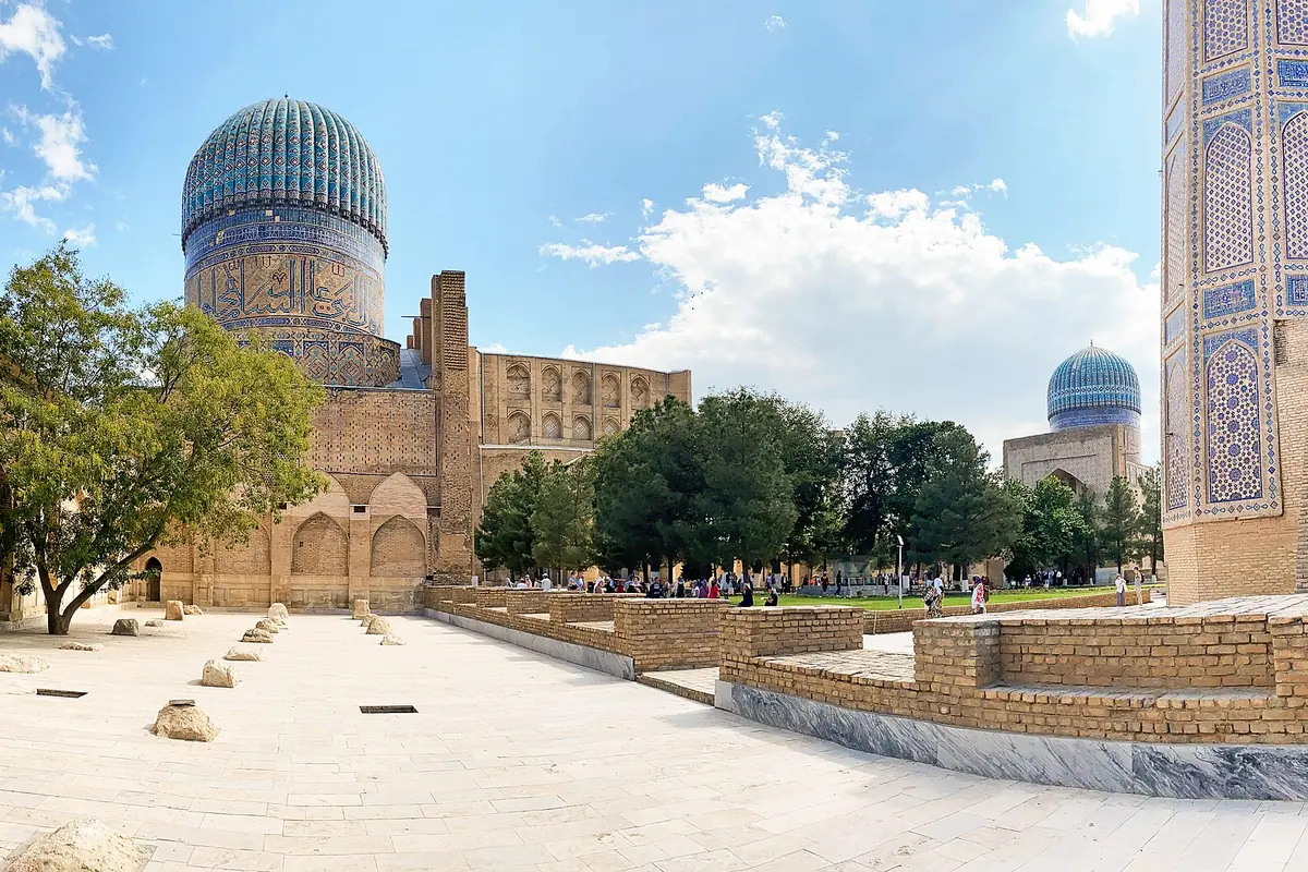 The ribbed blue dome of the Bibi-Khanym Mosque and its ruined courtyard in Samarkand under a partly cloudy sky