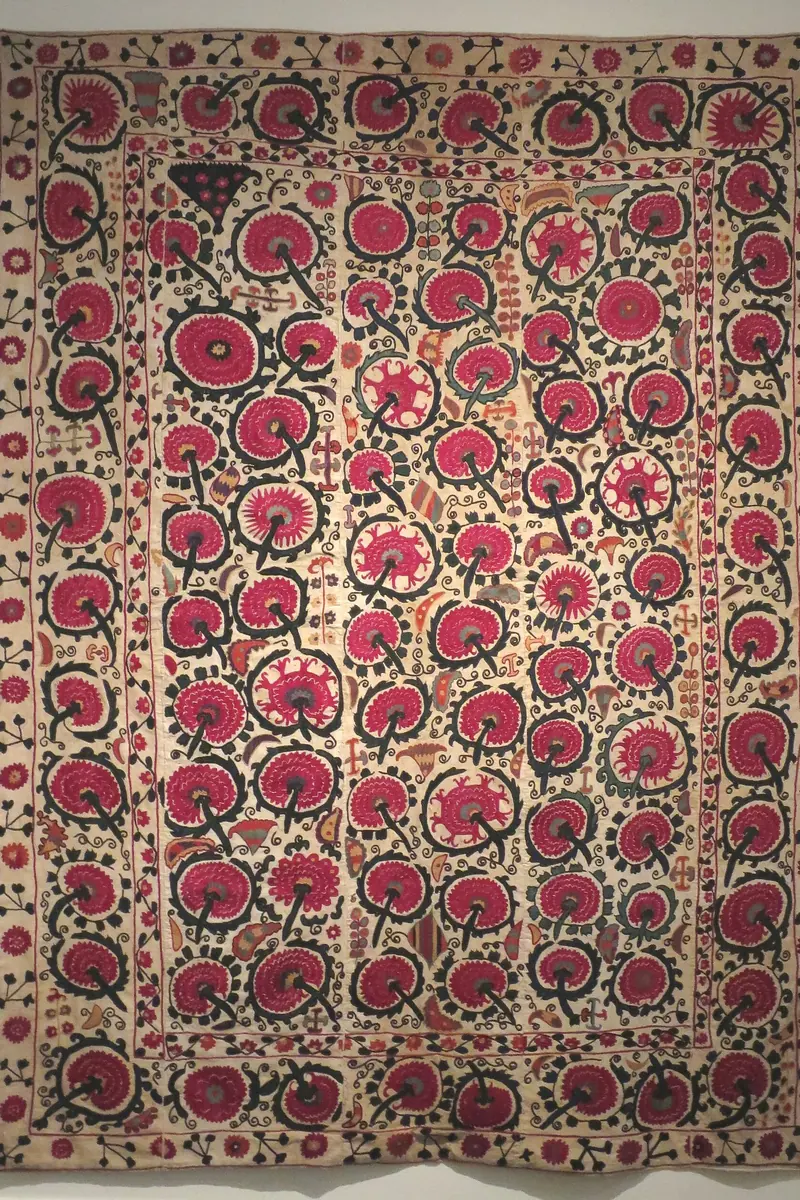 An Uzbek suzani, a cream cloth embroidered all over with large red and pink flower roundels